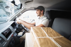 Delivery driver driving van with parcels on seat outside the warehouse-1