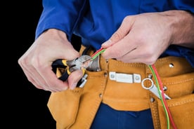 Electrician cutting wires against black