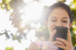 Happy brunette woman texting with her smartphone in a park