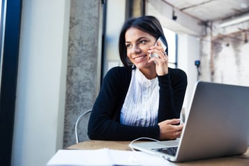 Happy businesswoman sitting at the table and talking on the phone in cafe. Looking away.jpeg