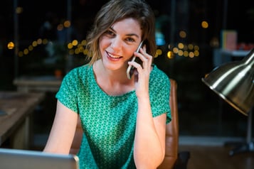 Portrait of businesswoman talking on mobile phone while working on laptop in the office