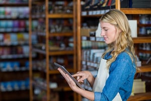 Smiling female staff using digital tablet in supermarket