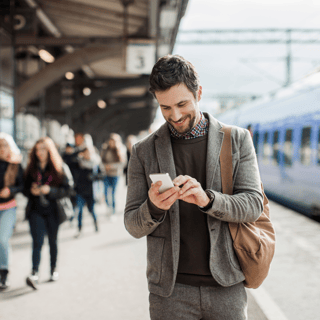 man texting on mobile at busy train station